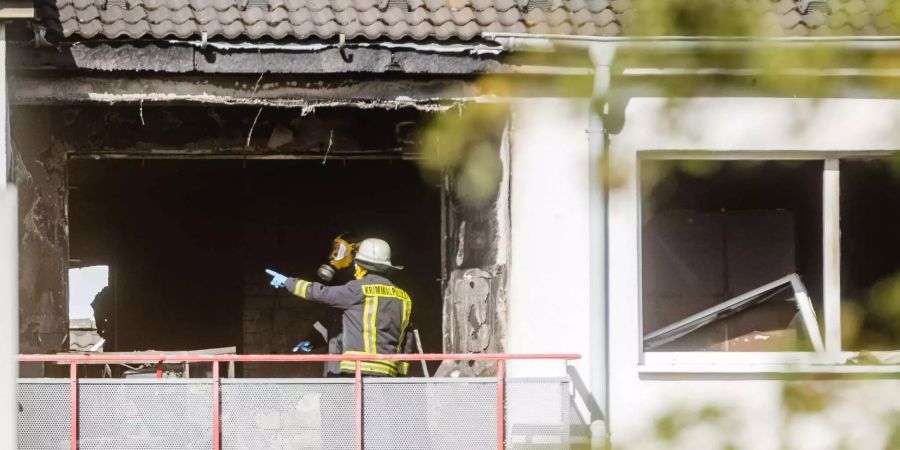 Kriminalbeamte stehen in der ausgebrannten Wohnung im Hamburger Stadtteil Eissendorf.