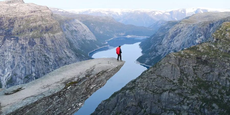 Ein Mann steht an der Spitze des Trolltunga-Felsvorsprungs über dem Ringedalsvatnet See in Norwegen.