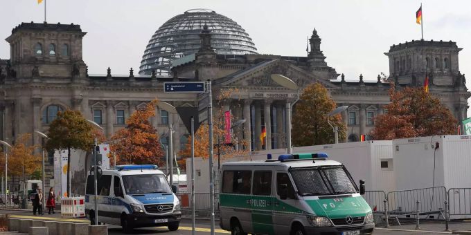 Zwei Polizeiautos fahren vor dem Reichstag in Berlin.
