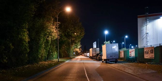 Eine Strasse wird im Industriegebiet Nord hinter einem Diskothekenareal nachts von Strassenlaternen erleuchtet.