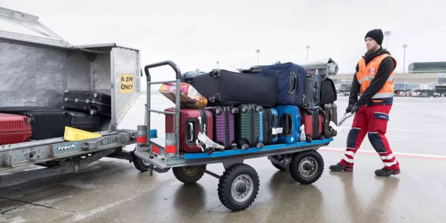 Ein Mitarbeiter entleert den Frachtraum eines Flugzeugs am Flughafen.