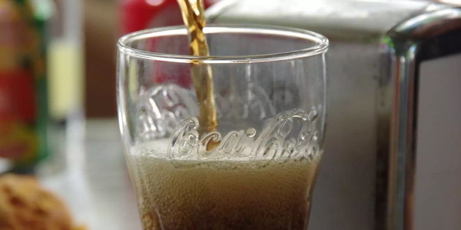 An einer Bar wird Coca-Cola in ein Glas gefüllt.