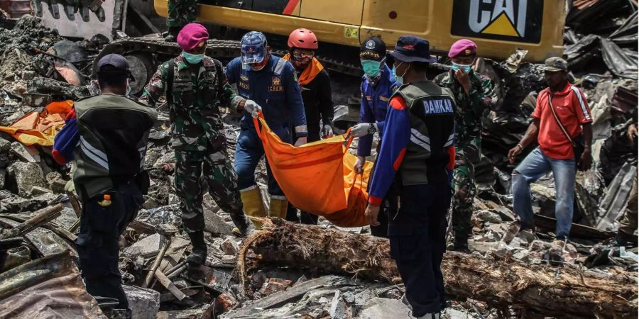 Indonesischer Rettungstrupps tragen den Leichensack eines Opfers während der Evakuierung des Dorfes Balaroa.