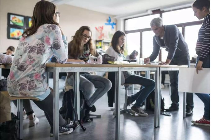 Ein Lehrer im Gespräch mit seinen Schülern und Schülerinnnen - Keystone Ein Lehrer im Gespräch mit seinen Schülern und Schülerinnnen - Keystone