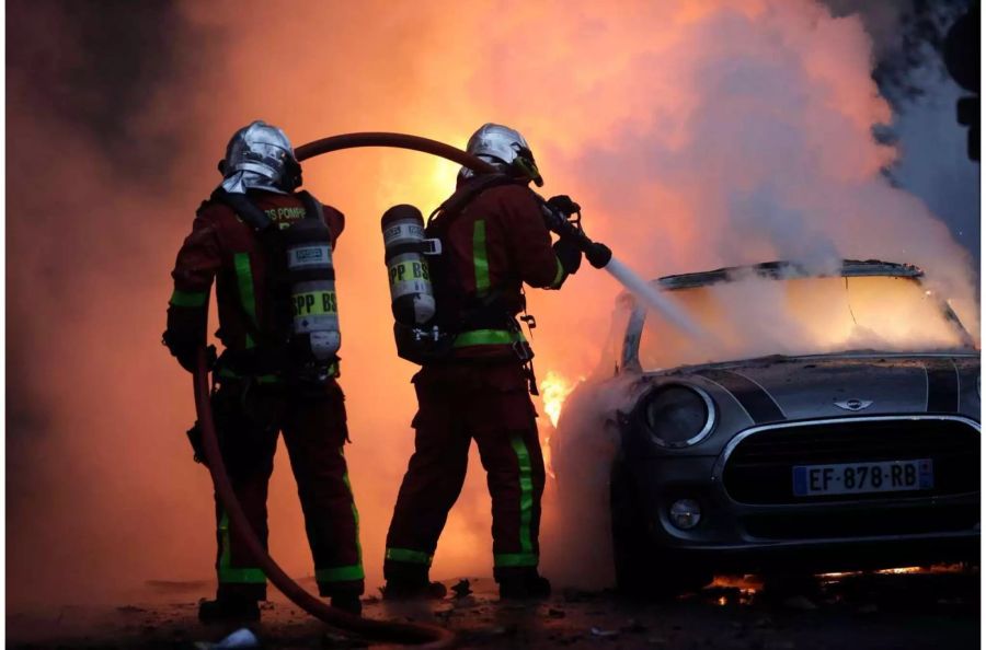 01.12.2018, Frankreich, Paris: Feuerwehrleute löschen bei einem Protest der sogenannten "Gelbwesten" in der Nähe der Champs-Elysees ein brennendes Auto. Die «Gelbwesten» gehen aus Protest gegen steigende Spritkosten und die Reformpolitik der Regierung auf die Strasse. Foto: Kamil Zihnioglu/AP/dpa +++ dpa-Bildfunk +++