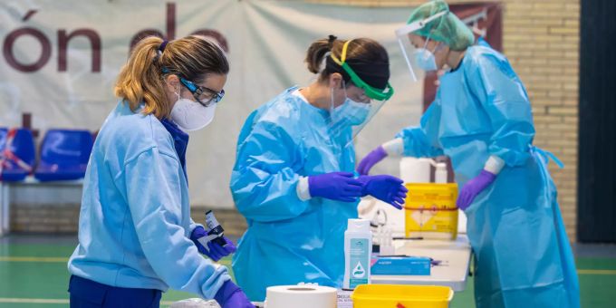 Drei Mitarbeiter des Gesundheitswesens tragen in Sevilla Schutzkleidung während sie in einer Corona-Schnellteststelle die Ergebnisse eines Massenscreening bearbeiten. Coronavirus - Spanien