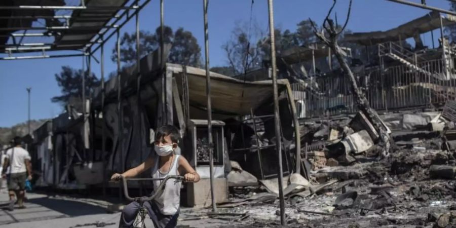 Junge vor verbrannten Trümmern in Moria. Dem Grossbrand vorangegangen waren Unruhen unter den Migranten, weil das Lager nach einem ersten Corona-Fall unter Quarantäne gestellt worden war. Foto: Petros Giannakouris/AP/dpa