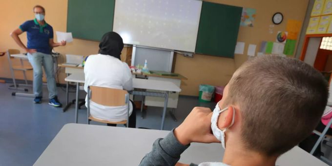 Schüler einer neunten Klasse einer Mittelschule sitzen zu Beginn des Unterrichts mit Mundschutz im Klassenzimmer. Erster Schultag