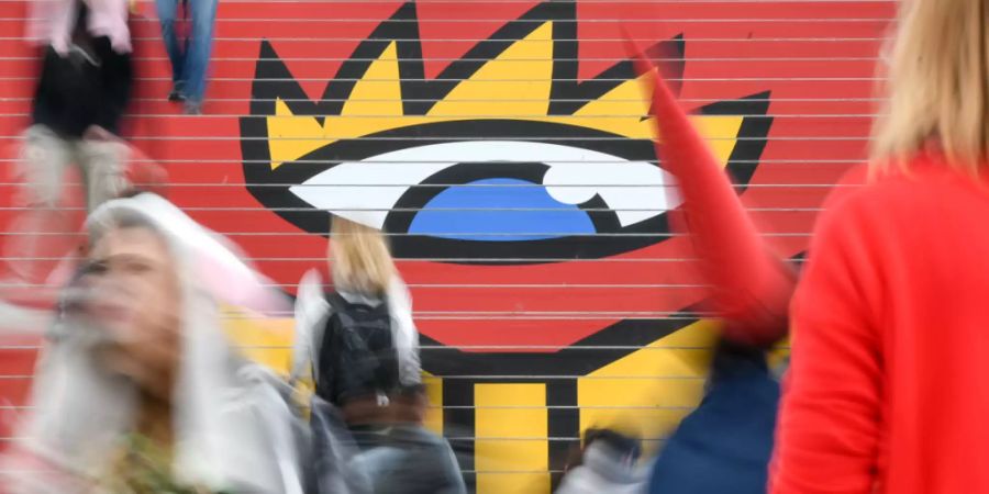 ARCHIV - Besucher gehen in der Glashalle über die Treppe mit dem Logo der Leipziger Buchmesse. Die Leipziger Buchmesse verschiebt ihren Termin im nächsten Jahr vom März auf Ende Mai. Foto: Jens Kalaene/dpa-Zentralbild/dpa