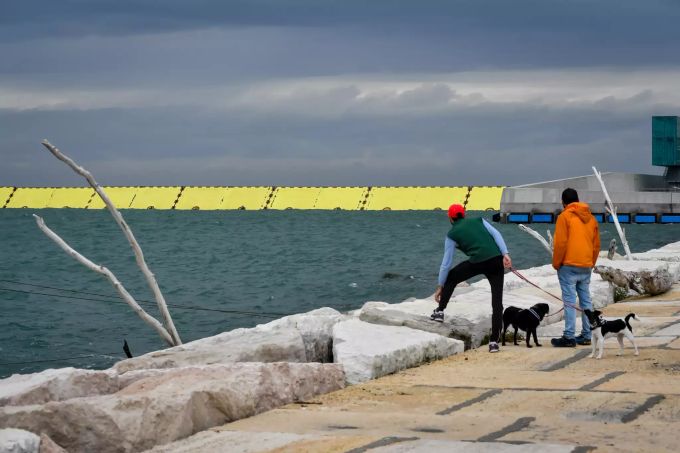 Zwei Passanten mit Hunden stehen am Wasser während die neue Hochwasserschutzanlage Mose hochgefahren ist. Foto: Claudio Furlan Unwetter Norditalien