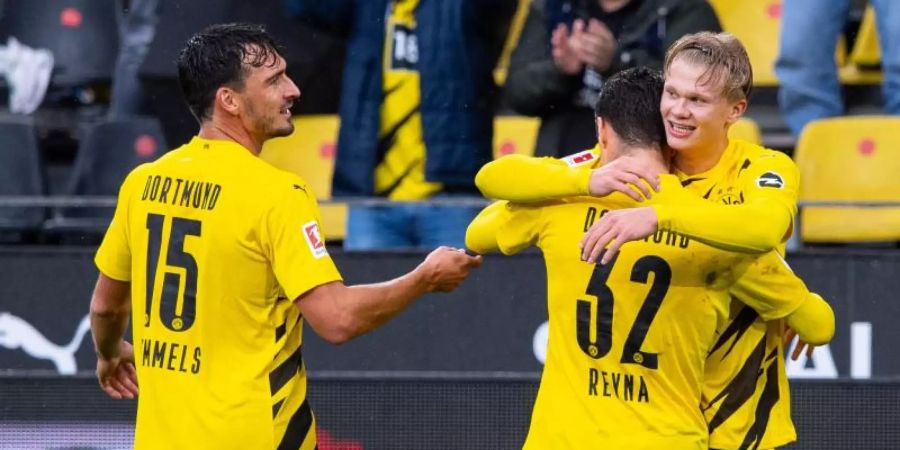 Mats Hummels (l) feiert mit dem Giovanni Reyna (32) umarmenden Erling Haaland einen Treffer im Spiel gegen den SC Freiburg. Foto: Guido Kirchner/dpa