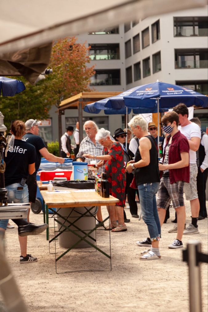 Menschen stehen Schlange vor dem Bratwurst Grill.