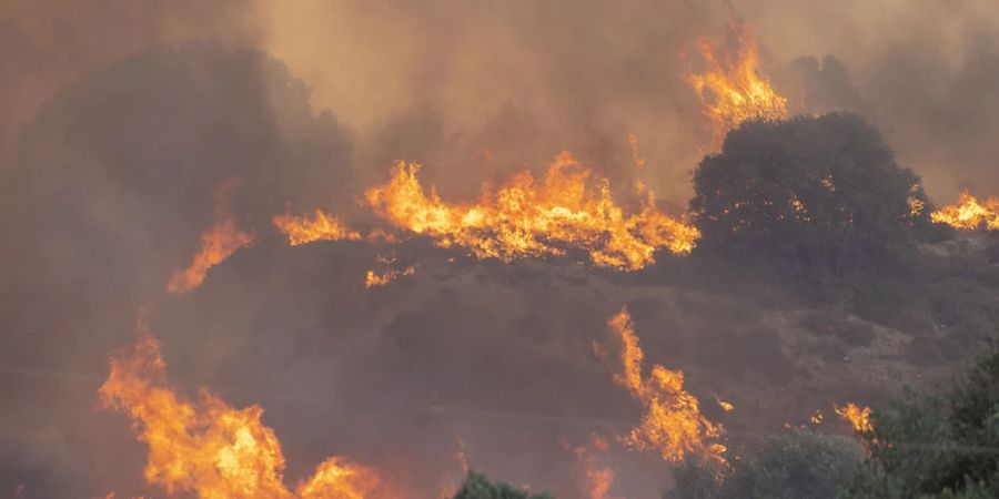 Am Mittag ist Nahe der Ortschaft Gennadi ein neuer Waldbrand ausgebrochen, am Abend erreichen die Flammen eine erste Siedlung, mehrere Häuser werden zerstört. Foto: Christoph Reichwein/dpa