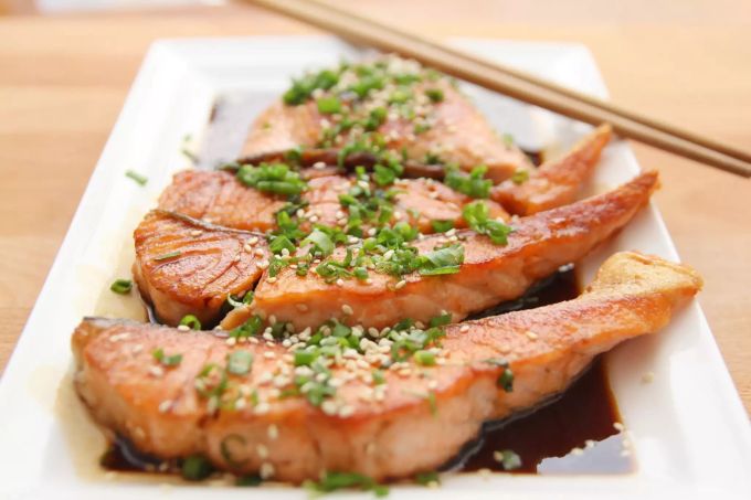 Mehrere mit Sesam, Kräutern und Teriyaki gewürzte Lachstranchen. Lachs