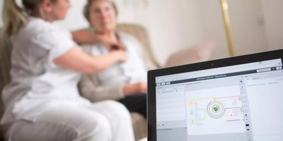 Eine Pflegerin legt einer Bewohnerin im Rahmen einer elektronischen Visite ein EKG-Gerät an, dass die Daten an einen Tablet-Computer und von dort aus zum Arzt überträgt.Foto: Marius Becker