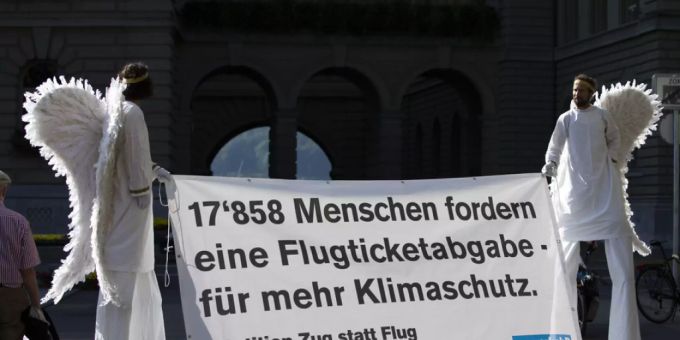 Aktivisten im Engelskostüm tragen am Dienstag ein Banner für die Petition «Ja zur Flugticketabgabe» vor das Bundeshaus. Flugticketabgabe