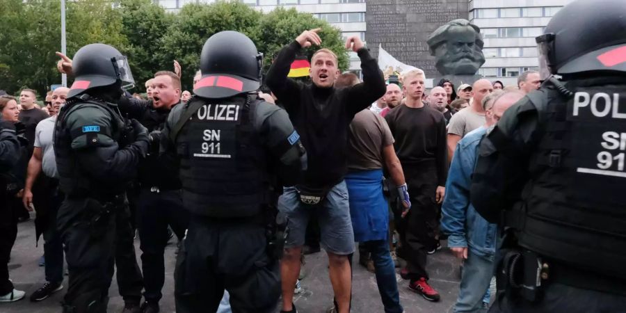 Chemnitzer Polizisten stehen in der Innenstadt bei einer Kundgebung der rechten Szene vor dem Karl-Marx-Denkmal, um ein Aufeinanderprallen von rechten und linken Gruppen zu verhindern.