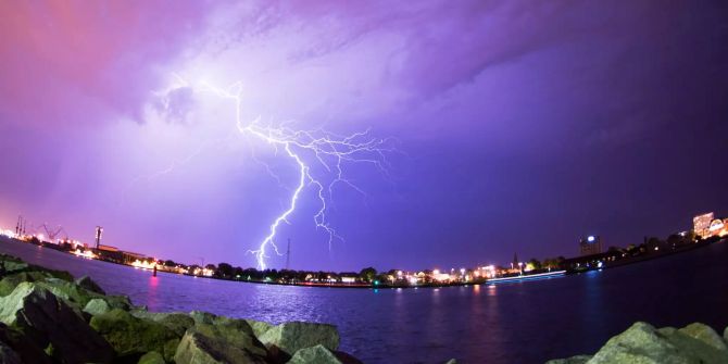 Blitze zucken während eines Gewitters über den Himmel eines Hafens.