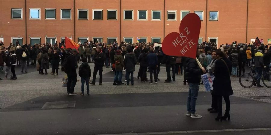 Ein Demonstrant hält auf dem Messeplatz in Basel ein Transparent mit dem Text «Herz statt Hetze».