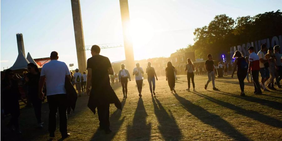 Besucher gehen beim zweitägigen Musikfestival Lollapalooza auf dem Gelände des Olympiaparks während des Sonnenuntergangs über eine Wiese.