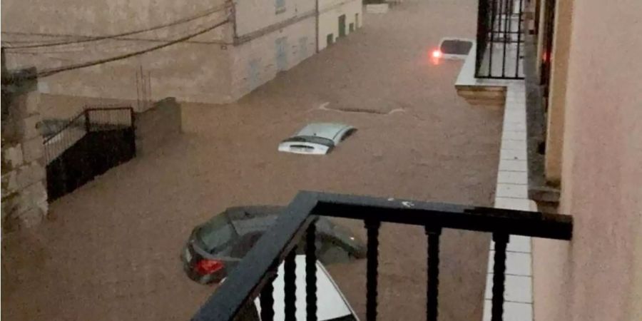 Pkw's stehen auf einer überfluteten Strasse auf Mallorca im Wasser.