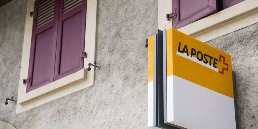 Ein altes Gebäude mit weinroten Fensterladen und "La Poste" Schild daran.