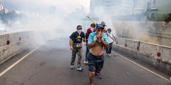 Demonstranten in Venezuela fliehen vor Tränengas. Demonstranten in Venezuela fliehen vor Tränengas.