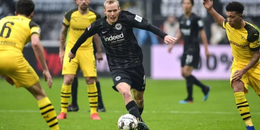 Frankfurts Sebastian Rode (M) versucht mit dem Ball zwischen den Dortmundern Thomas Delaney (l) und Jadon Sancho hinduch zu kommen. Foto: Silas Stein