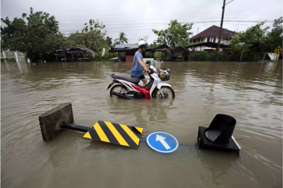 Ein Thailänder stösst seinen Töff in Pak Phanang durchs Wasser.