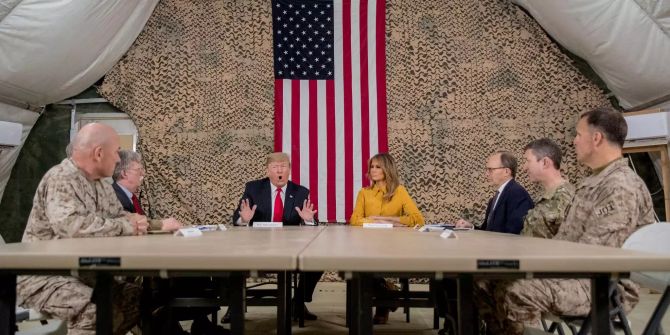 Donald und Melania Trump sitzen in einem Zelt im Irak vor Soldaten.