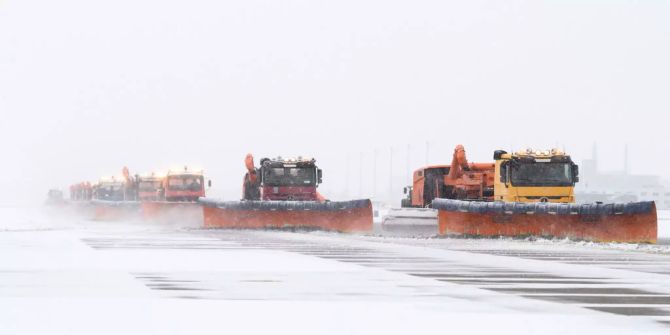 Räumfahrzeuge befreien das Rollfeld am Flughafen München von Schnee.