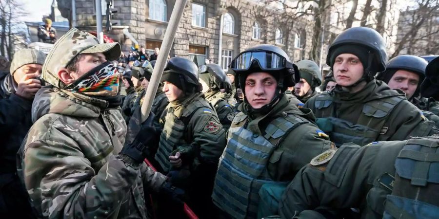 Demonstranten stehen neben Polizisten in Kiew.