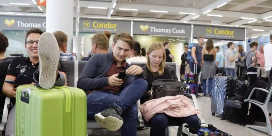 Passagiere warten in der Nähe des Büros von Condor und Thomas Cook im Flughafen von Palma de Mallorca. Foto: Clara Margais