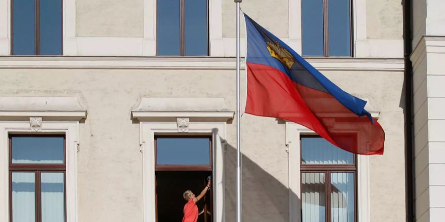 Ein Putzfrau putzt ein Fenster im Regierungsgebäude in Vaduz.