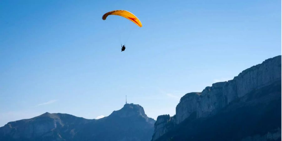 Ein Gleitschirm fliegt über die Ebenalp im Kanton Appenzell Innerrhoden im Hintergrund der Säntis.