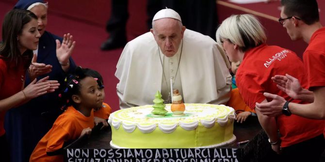 Papst Franziskus pustet eine Kerze auf einer Torte am Abend vor seinem 82. Geburtstag in der Vatikanischen Audienzhalle aus.