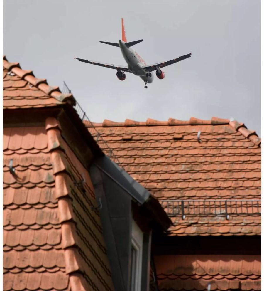 Flugzeug fliegt tief über ein braunes Hausdach hinweg - Keystone