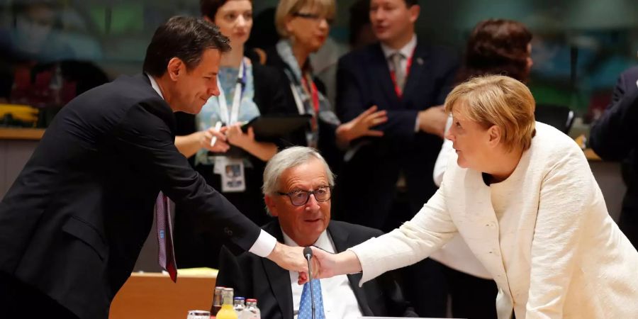 Bundeskanzlerin Angela Merkel (r) schüttelt bei einem Gespräch am Rundtisch auf dem EU-Gipfel dem italienischen Ministerpräsidenten Giuseppe Conte (l) die Hand. Jean-Claude Juncker (M), Präsident der Europäischen Kommission, sitzt dazwischen.