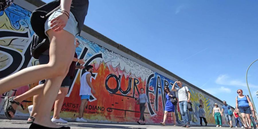 Passanten gehen an den Resten der Berliner Mauer, der heutigen East-Side-Gallery im Bezirk Kreuzberg-Friedrichshain, vorbei.