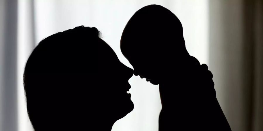 Die Silhouette einer Mutter mit ihrem drei Monate alten Baby.