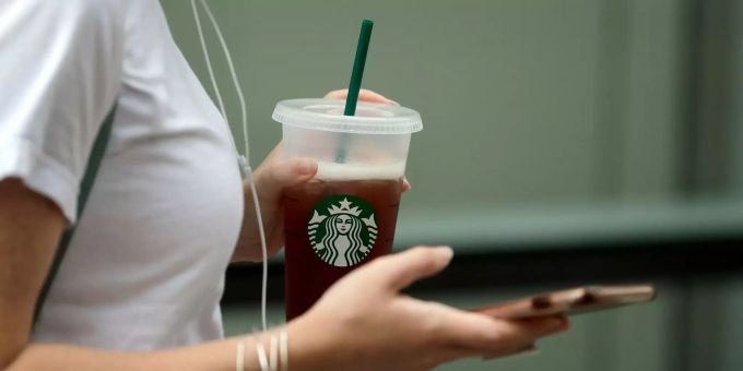 Starbucks macht mit Kaltgetränken Umsatz. Eine Frau hält einen Becher von Starbucks.