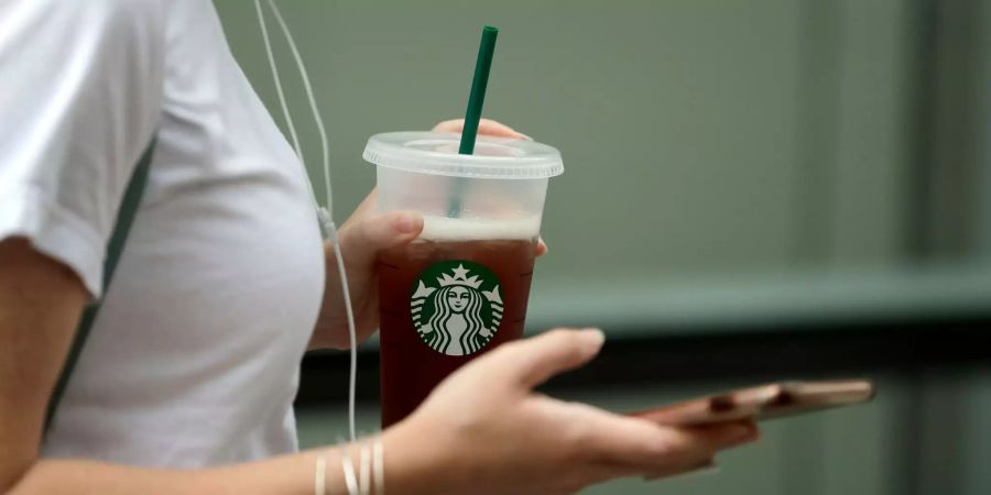 Eine Frau hält einen Becher von Starbucks.