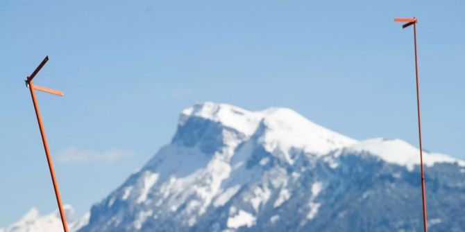 Baugespanne ragen vor dem Alpenpanorama empor.