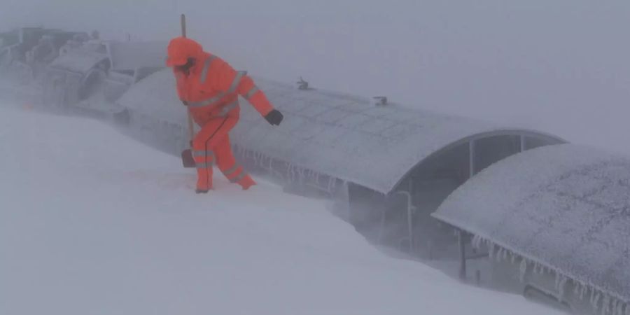 Ein Arbeiter versucht ein Zug vom Schnee zu befreien.