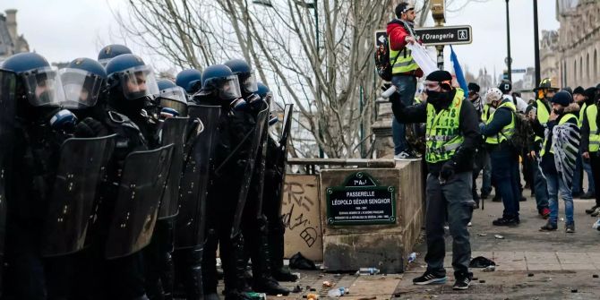 Polizisten stehen während eines Protests Gelbwesten gegenüber.