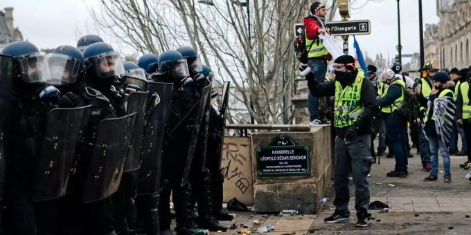 Polizisten stehen während eines Protests Demonstranten mit gelben Westen gegenüber. Polizisten stehen während eines Protests Gelbwesten gegenüber.