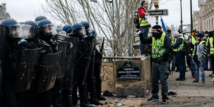 Polizisten stehen während eines Protests Gelbwesten gegenüber.