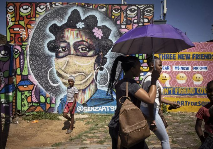 Einwohner von Soweto gehen vor einem informativen Graffiti-Kunstwerk, das die Bewohner von Soweto über die Gefahren des Coronavirus aufklärt, Johannesburg, Südafrika, 30. November 2021. South Africa Omicron variant