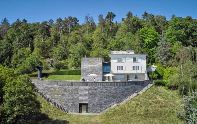 In dem weissen Haus in Neuenburg mit herrlichem Blick auf den See wohnte Friedrich Dürrenmatt fast 40 Jahre lang. In Schwarz gesellte sich im Jahr 2000 das mehrheitlich unterirdisch gelegene Centre Dürrenmatt hinzu. Die dunkle Farbe ist laut Botta ein Hinweis auf die sarkastische, dunkle Seite von Dürrenmatts Werk. s