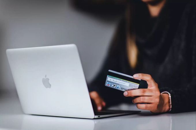 Verleitet Sie Ihre Umgebungssituation zum Einkauf? Frau vor Laptop mit Kreditkarte